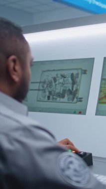 Havaalanı Terminali: Afrika kökenli Amerikan Güvenlik Subayı bilgisayar ekranlarında bagaj taraması yapıyor. Modern X-ray taraması Güvenlik Kontrol Noktasında. Dikey Çekim.