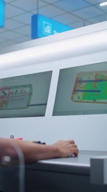 Afro-Amerikan Güvenlik Subayı, bavulunda şüpheli madde bulan yazılımları kullanarak bavul taramasını kontrol ediyor. Modern X-ray tarama teknolojisi havaalanı güvenlik kontrol noktasında. Dikey Çekim.