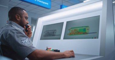 Havaalanı Güvenlik Kontrol Noktası: Afro-Amerikan Güvenlik Subayı PC Monitörlerinde X-ray Bavul Buluyor, Telsiz ile Bilgi Veriyor. Doli Vuruşu.