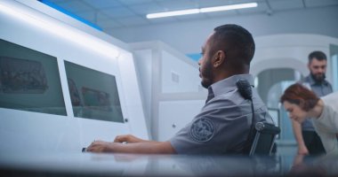 Havaalanı Güvenlik Kontrol Noktası: Afrikalı Amerikalı Güvenlik Subayı Bilgisayar ekranlarında bagaj taramasını görüntülüyor. Gelişmiş X-ray Tarama Teknolojisi Biniş Uçağı Uçağı.