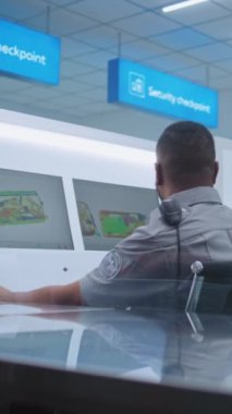 Havaalanı: Afrikalı Amerikan Güvenlik Subayı bilgisayar ekranlarında bagaj taramasını izliyor. Tarayıcı için kişisel eşyaları tepsilere koyan, Metal detektörü Gates 'i geçen yolcular. Dikey Çekim.