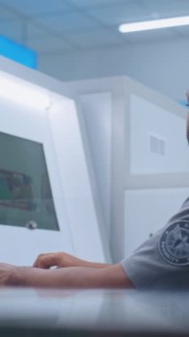 Havaalanı Güvenlik Kontrol Noktası: Afrikalı Amerikan Güvenlik Subayı Bilgisayar ekranlarındaki bagaj taramasını izliyor. Uçak Uçuşu için gelişmiş X-ray tarama teknolojisi. Dikey Çekim.