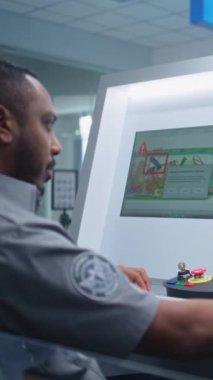 Havaalanı Güvenlik Kontrol Noktası: Afro-Amerikan Güvenlik Subayı, Bilgisayar ekranlarında bagaj taramasını izliyor, Bavulda Şüpheli Nesne Buluyor. Gelişmiş X-ray Tarama Teknolojisi.