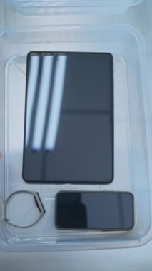 Kişisel Ögeleri Plastik Tepsiye yerleştiren Yolcuların En İyi Görünümü: Tablet Bilgisayar, Telefon, Çanta. Uçağa binmeden önce havaalanı güvenliği kontrol noktası. Güvenlik Subayı Prosedürü Denetliyor.