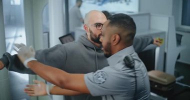 Havaalanı Terminali Güvenlik Kontrol Noktası: Afro-Amerikan Güvenlik Subayı Metal Detektörü Kapıları Taradıktan sonra Şüpheli Eşyalar İçin Adamın Vücudunu Denetliyor. TSA tarama prosedürleri. Turist Seyahate Çıktı.