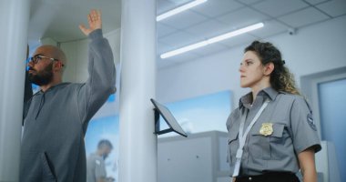 Havaalanı Terminali Güvenlik Kontrol Noktası: Afro-Amerikan Güvenlik Subayı X-ray taramasından sonra metal dedektörü kullanan adamı denetliyor. TSA tarama prosedürleri. Turist Tatile Çıkıyor.