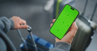 Havaalanı Terminali: Çantalı Adamın Kapanışı, Cep Telefonu Yeşil Krom Ekran Modeliyle Bekleme. İş Reklamcılığı ve Sosyal Medya İçeriği için Yer Tutucu ile Görüntü Şablonu.