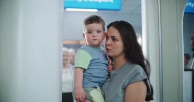 Havaalanı Terminali 'ndeki TSA Güvenlik Hattı: X-ray Metal Detektör Kapıları' ndan geçen çocuklu bir kadın. İnsan Vücut Tarama Prosedürü. Turistler Tatile Gidiyor.