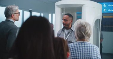 Havaalanı Güvenlik Kontrol Noktası: Afro-Amerikan Güvenlik Subayı Çeşitli Kişilerle, Yolcularla konuşuyor, Uçak Uçuşları için TSA tarama prosedürleri hakkında talimatlar veriyor. Turistler Tatile Gidiyor