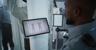 Havaalanı Güvenlik Kontrol Noktası: Afro-Amerikan Güvenlik Subayı, Tablet Bilgisayar Modern Yazılım kullanarak Yolcu Tarama Prosedürünü Denetliyor. Yetişkin Adam 'ın Uçak Uçuşu İçin Röntgen Taraması.