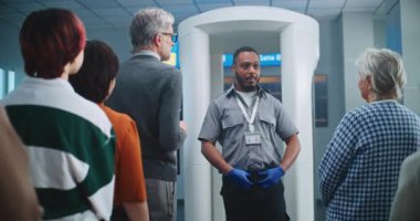 Havalimanı Güvenlik Kontrol Noktası: Afro-Amerikan Güvenlik Subayı çeşitli insanlara, yolculara uçağa binmek için TSA tarama prosedürleri hakkında bilgi veriyor. Tatil gezilerine çıkan Gezginler Kuyruğu.