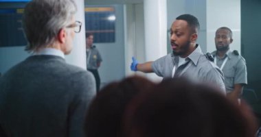 Havaalanı Güvenlik Kontrol Noktası: Afro-Amerikan Güvenlik Subayı Çeşitli Kişilerle, Yolcularla konuşuyor, Uçak Uçuşları için TSA tarama prosedürleri hakkında talimatlar veriyor. Turistler Tatile Gidiyor