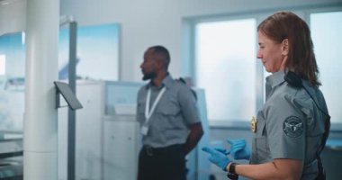 Havaalanı Terminali 'ndeki Güvenlik Kontrol Noktası: Kadın Güvenlik Subayı, Uçak Uçuşu için Şüpheli Eşyalar İçin Yaşlı Kadın Denetliyor. TSA tarama prosedürleri. Gezgin Tatile Çıkıyor.