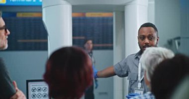 Havalimanı Güvenlik Kontrol Noktası: Afro-Amerikan Güvenlik Subayı çeşitli insanlara, yolculara uçağa binmek için TSA tarama prosedürleri hakkında bilgi veriyor. Tatil gezilerine çıkan Gezginler Kuyruğu.