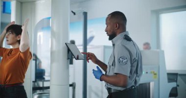 Havaalanındaki Ulaşım Güvenlik Hattı Metal Detektör Kapıları 'ndan geçen çeşitli insanlar. Afro-Amerikan Güvenlik Subayı Yolcuları Uçuş için kontrol ediyor, Tablet Bilgisayar kullanıyor.