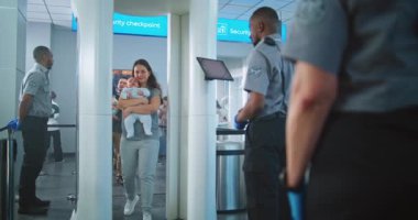 Havaalanı Terminali: Metal dedektör kapısından geçen iki çocuklu aile. Güvenlik görevlisi, Yolcuları Tablet Bilgisayar kullanarak Uçak Uçuşu için kontrol ediyor. Tarayıcı Bekleyen Turist Kuyruğu.