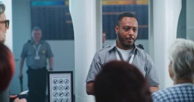 Havaalanı Güvenlik Kontrol Noktası: Afro-Amerikan Güvenlik Subayı çeşitli insanlarla, yolcularla konuşuyor, TSA Uçuş Tarama Prosedürleri ile ilgili talimatlar veriyor. Turistler Tatile Çıkıyor.