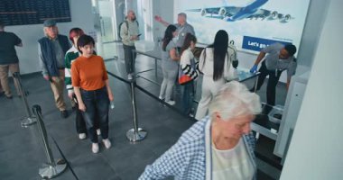 Havaalanı Terminalindeki Güvenlik Kontrol Noktası: Çeşitli İnsanlar Kuyruğu, Metal Detektör Taraması İçin Bekleyen Gezginler. Güvenlik görevlileri yolcuları kontrol ediyor, TSA tarama prosedürleri sağlanıyor. Yüksek Açı.