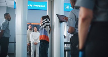 Havaalanı Terminali: Çeşitli Etnik Etkinlikler, Metal Detektör Taramasında Cinsiyet Ayrımı Yapanlar. Güvenlik görevlisi, Yolcuları Uçak Uçuşu için kontrol ediyor, Tablet Bilgisayar kullanıyor. Tarayıcı Bekleyen Turistler