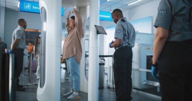 Havaalanı Terminali: Metal dedektöründen geçen çeşitli insanlar. Afro-Amerikan Güvenlik Subayı yolcuları Tablet Bilgisayar 'dan uçağa binmek için kontrol ediyor. Gezginler Tatile Çıkıyor.