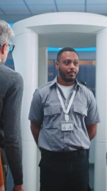 Havaalanı Güvenlik Kontrol Noktası: Afro-Amerikan Güvenlik Subayı, çeşitli kişilere, yolculara, uçağa biniş için TSA tarama prosedürleri hakkında bilgi veriyor. Gezginler Kuyruğu Seyahate Çıkıyor. Dikey Çekim