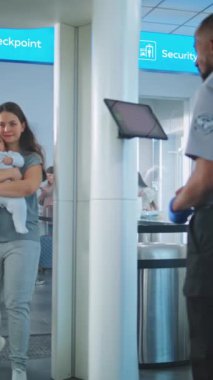 Havaalanı Terminali: Metal dedektör kapısından geçen iki çocuklu aile. Güvenlik görevlisi, Yolcuları Tablet Bilgisayar kullanarak kontrol ediyor. Tarayıcı Bekleyen Turistler Kuyruğu. Dikey Çekim.