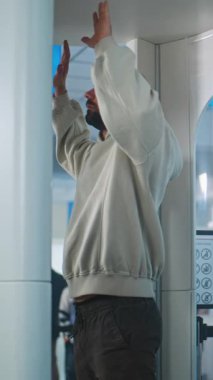 Havaalanındaki güvenlik kontrol noktası yetişkin adam metal dedektör kapısından geçiyor. Afro-Amerikan güvenlik görevlisi yolcuyu kontrol ediyor. Gezginler kuyruğu gösterimi bekliyor. Dikey Çekim.