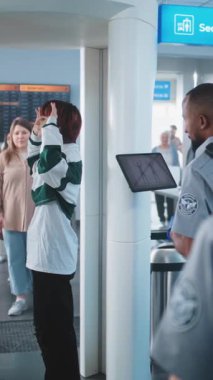 Havaalanındaki Ulaşım Güvenlik Hattı Metal Detektör Kapıları 'ndan geçen çeşitli insanlar. Afro-Amerikan Güvenlik Subayı Yolcu Taramasını Kontrol Ediyor, Tablet Bilgisayar kullanıyor. Dikey Çekim.