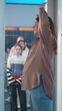 Havaalanı Terminali: Metal dedektör kapısından geçen çeşitli insanlar. Güvenlik Subayı, Yolcuları Tablet Bilgisayar 'dan uçağa binmek için kontrol ediyor. Gezginlerin Kuyruğu Ekranı Bekliyor