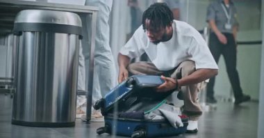 Uluslararası Havaalanı Terminali 'ndeki güvenlik kontrol noktası: Afro-Amerikan bir adam uçağa binmeden önce bavulunu kontrol ediyor. TSA Tarama Prosedürlerinden Geçen Çeşitli İnsanlar, Gezginler.