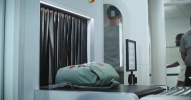 Havalimanı Güvenlik Kontrol Noktası 'ndaki tarama prosedürleri: TSA İşçisi, X-ray Metal Detektörü ile kişisel eşyaları ve bagajları konveyör bandına koydu. Çeşitli İnsanlar İnsan Vücut Tarayıcıları Arasında Yürüyor.