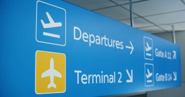 Mavi Seyrüsefer tabelası yolcuları uçak biletleri, terminaller ve kapılar için tavanda asılı olan yolculara yönlendiriyor. Yoğun Modern Uluslararası Havaalanı Terminali 'nde Navigasyon İşareti. Kapat..