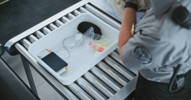 Havaalanı Terminalindeki Güvenlik Kontrol Noktası: Güvenlik Subayının bavulları kontrol etmesi, X-ray taraması için Tepsilerdeki Yolcuların Kişisel Eşyaları. TSA tarama prosedürleri. Yüksek Açı Kapat.