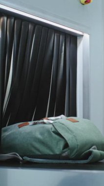 Havaalanı Güvenlik Kontrol Noktası: TSA çalışanı, yolcuların bagajlarını ve kişisel eşyalarını X-ray Metal Detektörü ile konveyör bandına yerleştirdi. Uçağa binmeden önce tarama prosedürleri. Dikey Çekim.