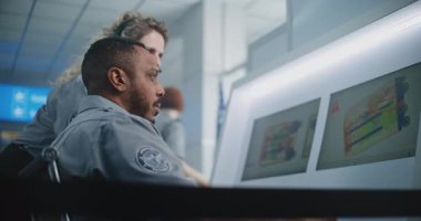 Havaalanı Güvenlik Kontrol Noktası: İki Çoklu Etnik Güvenlik Memuru Bilgisayar Yazılım Kullanarak Bilgisayar Ekranlarındaki Bagaj Resimlerinin X-ray Taramasını Analiz Ediyor. Metal dedektöründe Gelişmiş Tarama İşlem Teknolojisi.