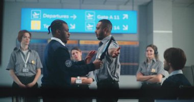 Havaalanı Personel Eğitimi: Metal Detektörü ile Yolcuların Tarama Sürecini Gösteren Afro-Amerikan Güvenlik Görevlisi, İşçi Grubuna Talimat Veriyor. Uçağa binmek için tarama prosedürleri.