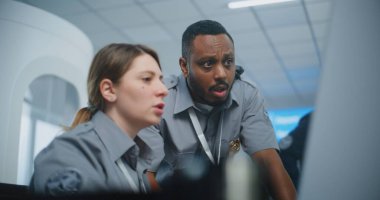 Güvenlik Kontrol Noktası Havaalanı Personeli: Üniformalı Konuşan, TSA Tarama Prosedürlerini Analiz eden İki Çok Irklı Güvenlik Memuru Bilgisayar Kullanıyor. Seyahat Güvenliği Ulaştırma Güvenlik Yönetimi.