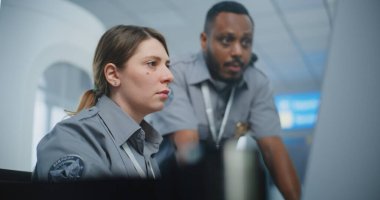 Güvenlik Kontrol Noktası Havaalanı Personeli: Üniformalı Konuşan, TSA Tarama Prosedürlerini Analiz eden İki Çok Irklı Güvenlik Memuru Bilgisayar Kullanıyor. Seyahat Güvenliği Ulaştırma Güvenlik Yönetimi.