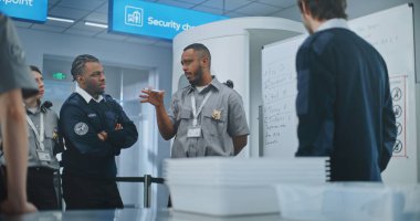 Havaalanı Güvenlik Personel Eğitimi: Profesyonel Afro-Amerikan TSA Görevlisi Planlama Oturumu Yapıyor, Whiteboard Kullanıyor, İşçi Takımına Talimatlar Veriyor. Ulaştırma Güvenlik Yönetimi.