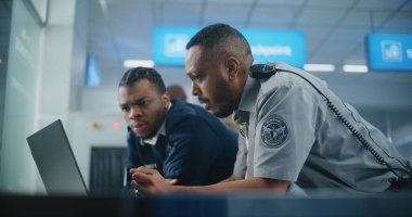 Havaalanı Güvenlik Kontrol Noktası: Laptop Bilgisayar ve Konuşan Afro-Amerikan Güvenlik Memurları. Seyahat Güvenliği Ulaştırma Güvenlik İdaresi. Arka planda, havaalanı personeli çalışıyor.