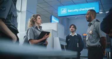 Havaalanı Personel Brifingi: Tablet Bilgisayarlı Kadın TSA Görevlisi, Kontrol Noktasında İşçi Grubu 'na Yolcuların Tarama Süreci ve Uçuş için Tarama Yöntemleri Hakkında Bilgi Veriyor.