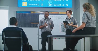 Havaalanı Güvenlik Personel Brifingi: Profesyonel Afro-Amerikan TSA Görevlisi, Dijital Aygıtlı İşçi Grubuna Eğitim Veriyor. Ulaştırma Güvenlik Yönetimi