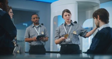 Havaalanı Personel Brifingi: Kadın Güvenlik Subayı Eğitim Veriyor, Uçuş Kartını tutuyor, İşçi Takımına Prosedürleri ve Ayrıntıları Açıklıyor. Ulaştırma Güvenlik Yönetimi.