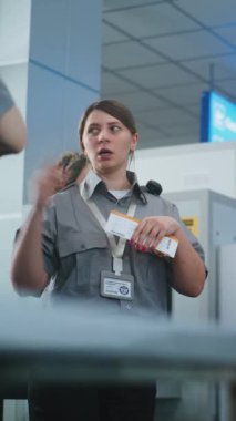 Havaalanı Personel Brifingi: Kadın Güvenlik Subayı Eğitim Veriyor, Uçuş Kartını tutuyor, İşçi Takımına Prosedürleri Açıklıyor. Ulaşım Güvenlik İdaresi. Dikey Çekim.