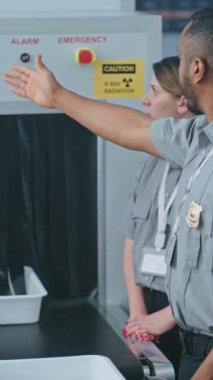 Havaalanı Güvenlik Kontrol Noktası: Afro-Amerikan Ulaşım Güvenliği Memuru, Havalimanı Personeline Metal Detektör Taşıyıcı Kayışı ve Tarama İşlemleri hakkında X-ray taraması talimatı verdi. Dikey Çekim.