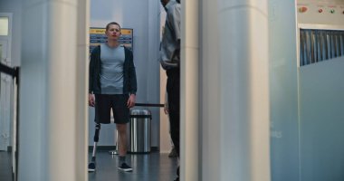 Güvenlik Kontrol Noktasındaki Çeşitli Gezginler: Protez bacaklı adam ve X-ray Metal dedektöründen geçen yetişkin kadın havaalanı terminalinde. Uçağa binmek için yolcu tarama prosedürleri.