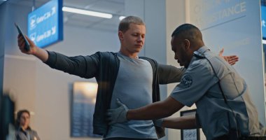 Havaalanı Terminali 'ndeki güvenlik kontrol noktası: Afro-Amerikan Güvenlik Subayı, Biniş Uçuşu için Protez Ayaklı Genç Adamı Denetliyor. TSA tarama prosedürleri. Engelli Turist Seyahate Çıktı