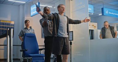 Güvenlik Kontrol Noktası: Afro-Amerikan Ulaşım Güvenliği Memuru Adamı Havalimanı Terminali 'ndeki tekerlekli sandalyede biyonik protez bacakla kontrol ediyor. Uçağa binmek için yolcu tarama prosedürü. Engelli Yolcu