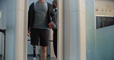 Havaalanı Terminalindeki güvenlik kontrol noktası: Protez bacaklı bir adam ve Metal dedektöründen geçen yetişkin bir kadın biniş için kapıları tarıyor. TSA tarama prosedürleri sırasında çeşitli turistler.