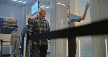 Güvenlik Kontrol Noktasındaki Kıdemli Gezgin: Tekerlekli sandalyeden kalkan yaşlı adam, Havaalanı Terminali 'ndeki X-ray Metal Detektör Tarayıcısını geçiyor, Havaalanı Personel Yardımcısı. Yolcu Ekran Prosedürleri.